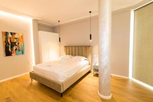 een slaapkamer met een wit bed en een paal bij Nikaj Premium Apart-Hotel in Vlorë