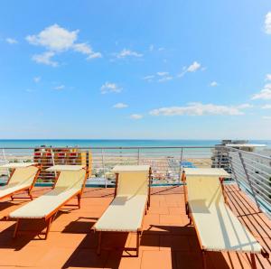 una fila di sedie su un balcone con vista sull'oceano di Hotel Ali d'Oro a Rimini