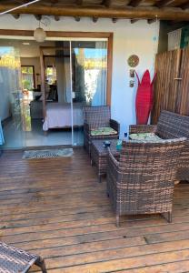 una terrazza con sedie in vimini e un letto in una camera da letto di Flores do Mar a Arraial d'Ajuda