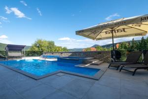 a swimming pool with an umbrella and chairs on a patio at Villa Kula in Bihać