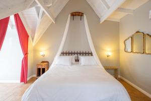 a bedroom with a white bed with a red curtain at Atelier Hotel Charme & Spa in Villa General Belgrano +71 photos