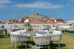 a bunch of chairs and tables with a table and a mountain at GRAND PATELLI in Myrina