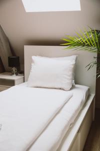 ein weißes Bett mit einem weißen Kissen und einer Pflanze in der Unterkunft Apartamenty Leszno in Leszno