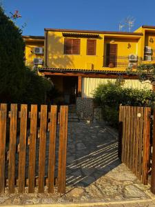 a wooden fence in front of a yellow house at Villetta Vista Mare Cornino in Custonaci
