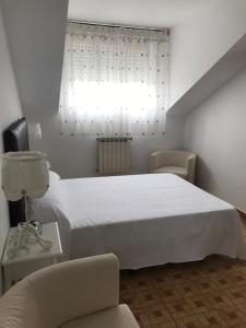a bedroom with a white bed and a window at Hostal Casa Enrique in Barres