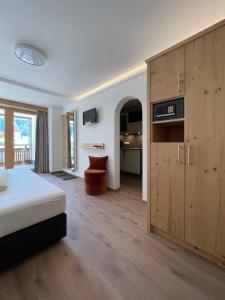 a bedroom with a bed and a large wooden cabinet at Hotel & Suites Glück Auf in Mayrhofen
