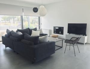 a living room with a black couch and a tv at Casa Lagada Kos Private Residence. in (( Kermetés ))
