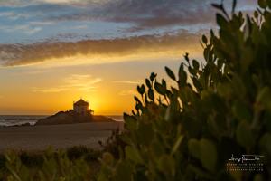 ein Leuchtturm am Strand bei Sonnenuntergang in der Unterkunft Casa da Praia em Valadares in Vila Nova de Gaia