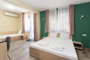 1 dormitorio con 2 camas y pared verde en Къща за гости Перуника, en Sapareva Banya
