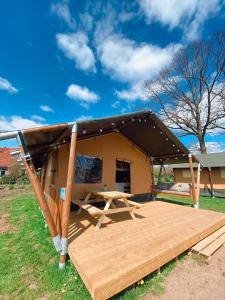 a tent with a wooden deck and a picnic table at camping?glamping morskersweitje in Winterswijk