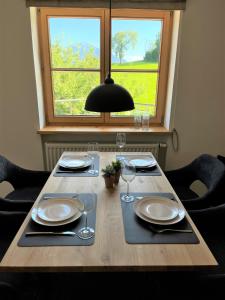 una mesa de madera con platos y gafas y una ventana en Mein Traumblick, en Rettenberg