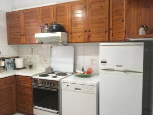 a kitchen with white appliances and wooden cabinets at Vintage Beach House in Alexandroupoli