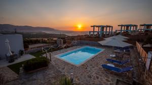 a pool with chairs and an umbrella and the sunset at Dreams Villa Luxury Residence in Sissi
