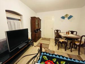 - un salon avec une télévision, une table et des chaises dans l'établissement Casa bunicilor, à Nădăştia de Sus