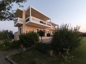 a house with a balcony and bushes at Aktaion Apartments in Samothraki