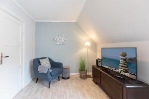ein Wohnzimmer mit einem TV und einem blauen Stuhl in der Unterkunft Tante Tine in Husum