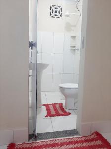 a bathroom with a toilet and a red rug at Apart Hotel M6D in Rio Branco