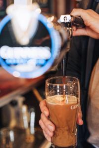 a person is pouring a drink into a glass at The Bull Inn in Woolpit