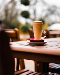 una tazza di caffè seduta sopra un tavolo di The Bull Inn a Woolpit