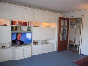 a living room with a tv and white cabinets at Lornsenhof App 6 in Westerland