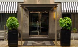 a glass door to a building with two potted plants at The Marcel at Gramercy in New York