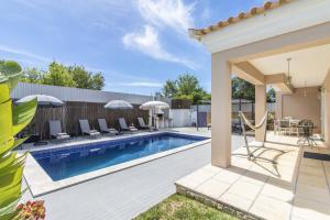 a pool with chairs and umbrellas in a backyard at Villa Maya by Algarve Holidays in Almancil