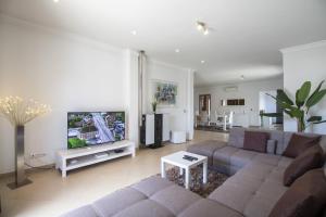a living room with a couch and a flat screen tv at Villa Maya by Algarve Holidays in Almancil