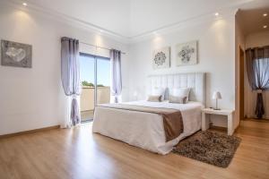 a white bedroom with a bed and a large window at Villa Maya by Algarve Holidays in Almancil +16 photos