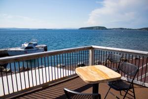 a wooden table and chairs on a balcony with a boat at Dildo Boathouse Inn in Dildo