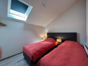 1 dormitorio con 2 camas con sábanas rojas y ventana en Sakura Lodging en Bossut-Gottechain
