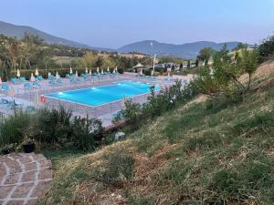 ein großer Pool auf einem Hügel mit Stühlen in der Unterkunft Il Pozzo Country House in Collescipoli