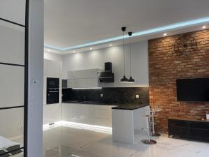a kitchen with white cabinets and a brick wall at Apartament Centrum in Bydgoszcz