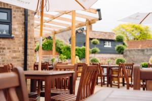 a row of tables and chairs with umbrellas on a patio at The Bull Inn in Woolpit +42 photos