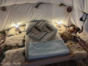 Una cama con almohadas y un libro. en Romantic Wildlife Tipi Teepee Tomnatic Bihor Romania Apuseni, en Tomnatic