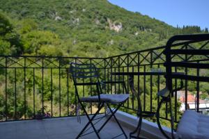 2 Stühle und ein Tisch auf einem Balkon mit Bergblick in der Unterkunft Giannatos Studios- Isabella in Póros
