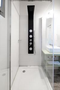 ein weißes Bad mit einer Dusche und einem Waschbecken in der Unterkunft Atelier Hotel de Charme in Villa General Belgrano