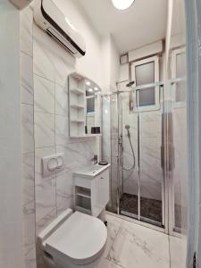 a white bathroom with a shower and a toilet at Green garden in Zagreb