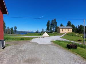 un camino de grava con una casa en la distancia en Villmarksgård camping en Hattfjelldal