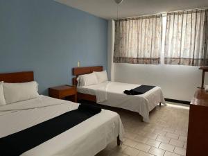 a hotel room with two beds and a window at Hotel Italia in Aguascalientes