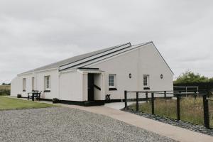 Fisherman's Cottage في Vatsker: مبنى ابيض بسقف اسود وسياج