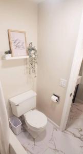 a white bathroom with a toilet and a picture on the wall at Burke Abode - Trailside Condo with King & Full Beds in East Burke