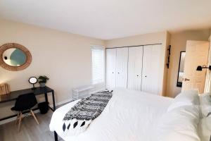 a bedroom with a large white bed and a desk at Burke Abode - Trailside Condo with King & Full Beds in East Burke