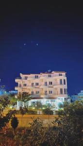 - un grand bâtiment blanc la nuit dans l'établissement MARIKSEL Hotel, à Ksamil