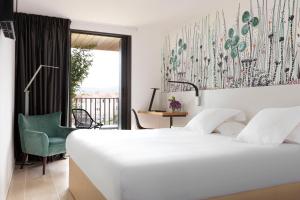 - une chambre avec un lit blanc et une chaise verte dans l'établissement Hotel Alcyon, à Porto-Vecchio