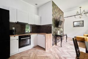 una cocina con armarios blancos y horno negro en Art Apartment Grzmiąca, en Grzmiąca