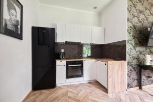 Una cocina con gabinetes blancos y un refrigerador negro. en Art Apartment Grzmiąca, en Grzmiąca