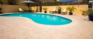 a swimming pool in a yard with chairs and an umbrella at Spacious Villa with Ocean and Mountain view-4 beds in Cul de Sac