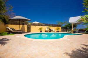 una piscina con sombrilla y un patio en Spacious Villa with Ocean and Mountain view-4 beds en Cul de Sac