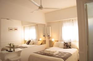 a white bedroom with two beds and a mirror at Tamanacos Hotel & Spa in Villa Gesell +40 photos