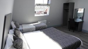 a bedroom with a bed and a desk in it at Roshni Hotel in Southall +1 photo